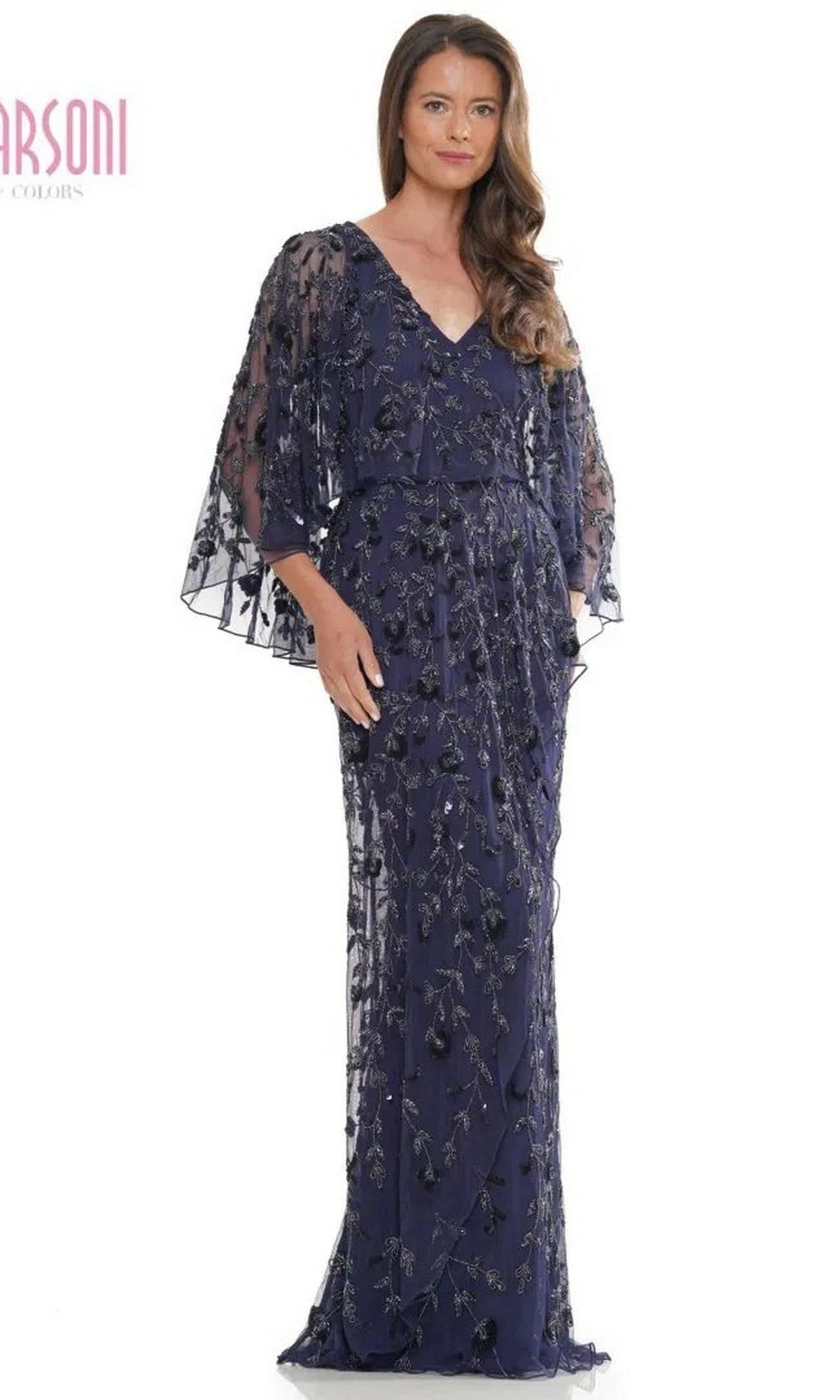 A woman stands facing forward against a plain background wearing the Marsoni MV1282 long formal dress in navy, featuring sequin and beaded leaf appliques, sheer flared sleeves, and a wrap-style column skirt.